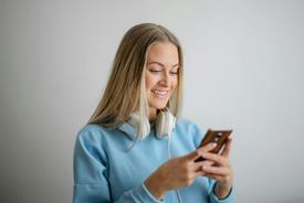 foto: vrouw in blauw shirt met lange mouwen met bruine smartphone